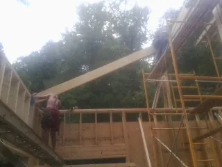 Carpenter raising a rafter beam on a new second story frame in Junction City